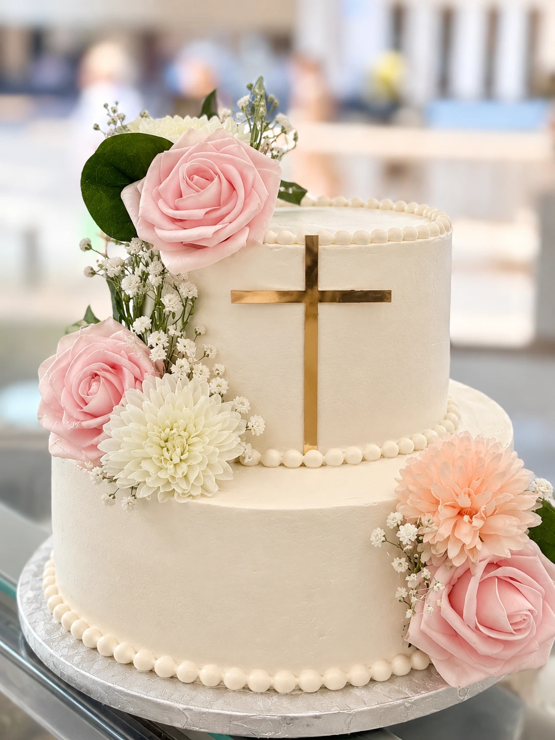 Tarta de primera comunión de dos pisos en blanco, con flores y cruz dorada